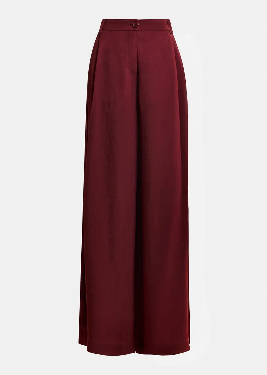 Essentiel Antwerp's Inovember Satin Pants in burgundy feature a high waist, wide-leg silhouette, relaxed fit, flowing satin fabric, and button-zip closure, shown against a plain white background.