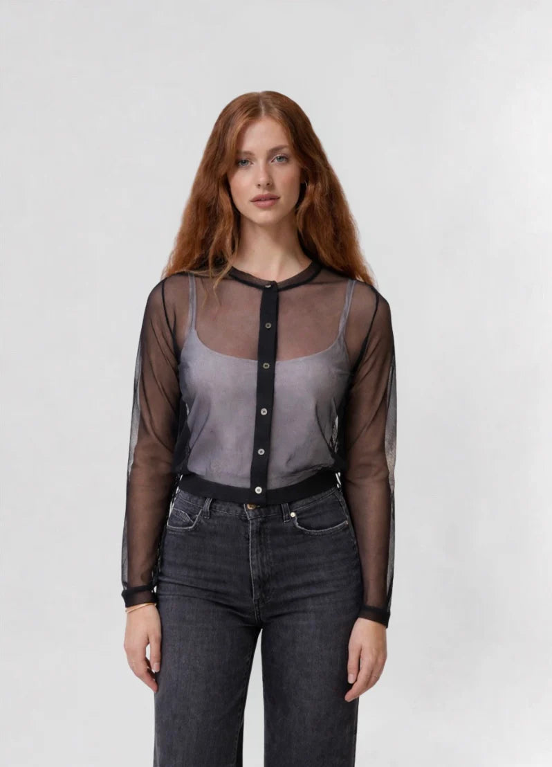 A woman with long red hair models the Emin and Paul Sheer Cardigan in black, layered over a gray tank and dark jeans, against a plain light background.