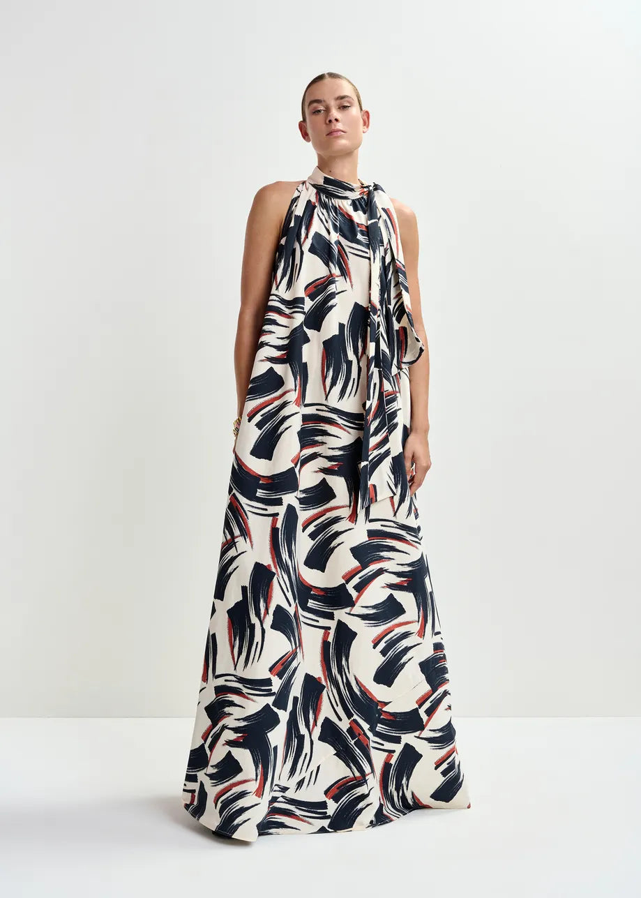 Model wearing the Essentiel Antwerp Jayda High Neck Maxi Dress in Burned Red, featuring a sleeveless A-line silhouette and abstract black, white, and red brushstroke pattern, against a plain white background.