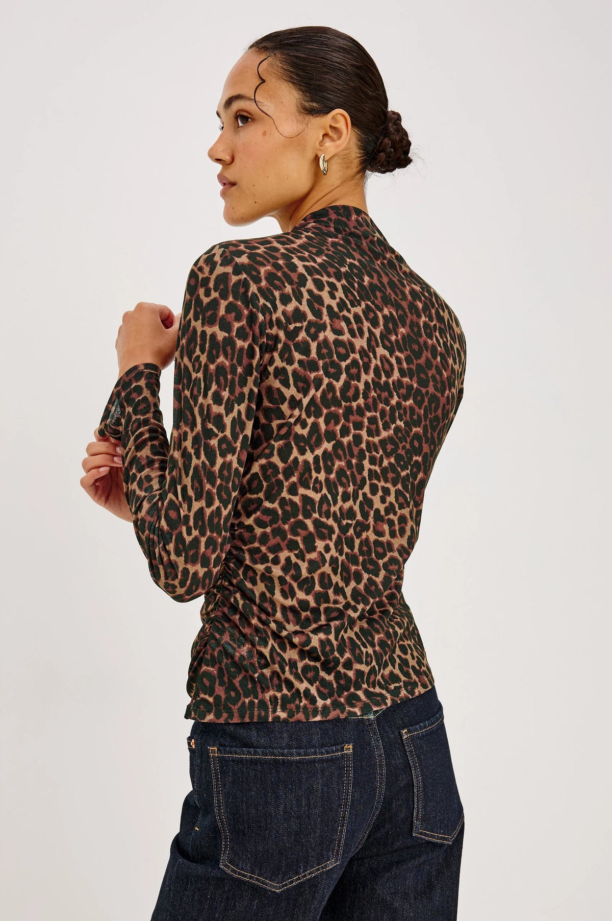 A model wears the Rails Joelle Top - Brown Nala, a long-sleeved, funnel neckline mesh top in a brown and black leopard print, paired with dark wash jeans.