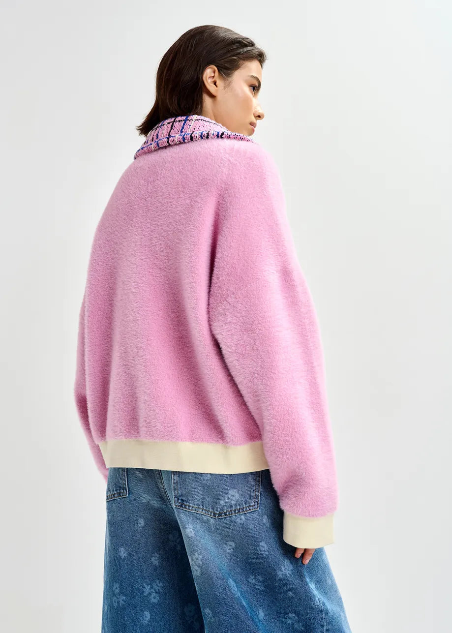 A person wearing the Essentiel Antwerp Joilu Contrast Knit Cardigan in pink, styled with wide-leg blue jeans, stands against a plain light background.