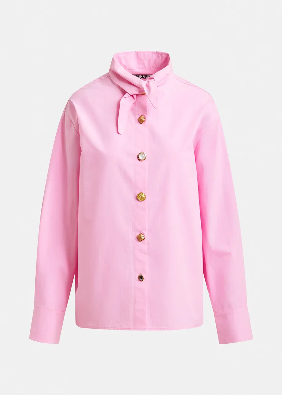 The Essentiel Antwerp Jomato Pointed Collar Shirt in pink is a long-sleeve cotton top with a high collar, small tied bow, and jewel buttons, shown on a plain white background.