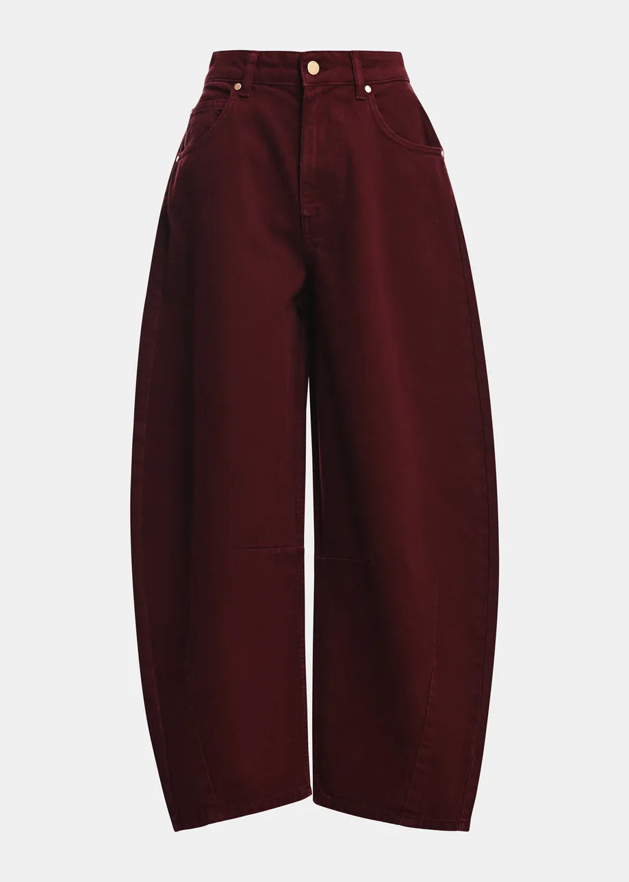 The Kokos Colour Denim Barrel Leg Jeans in Burgundy by Essentiel Antwerp are high-waisted jeans with a barrel-leg silhouette, crafted from 100% organic cotton. They feature front and back pockets, belt loops, and a button closure, and are shown against a plain white background.