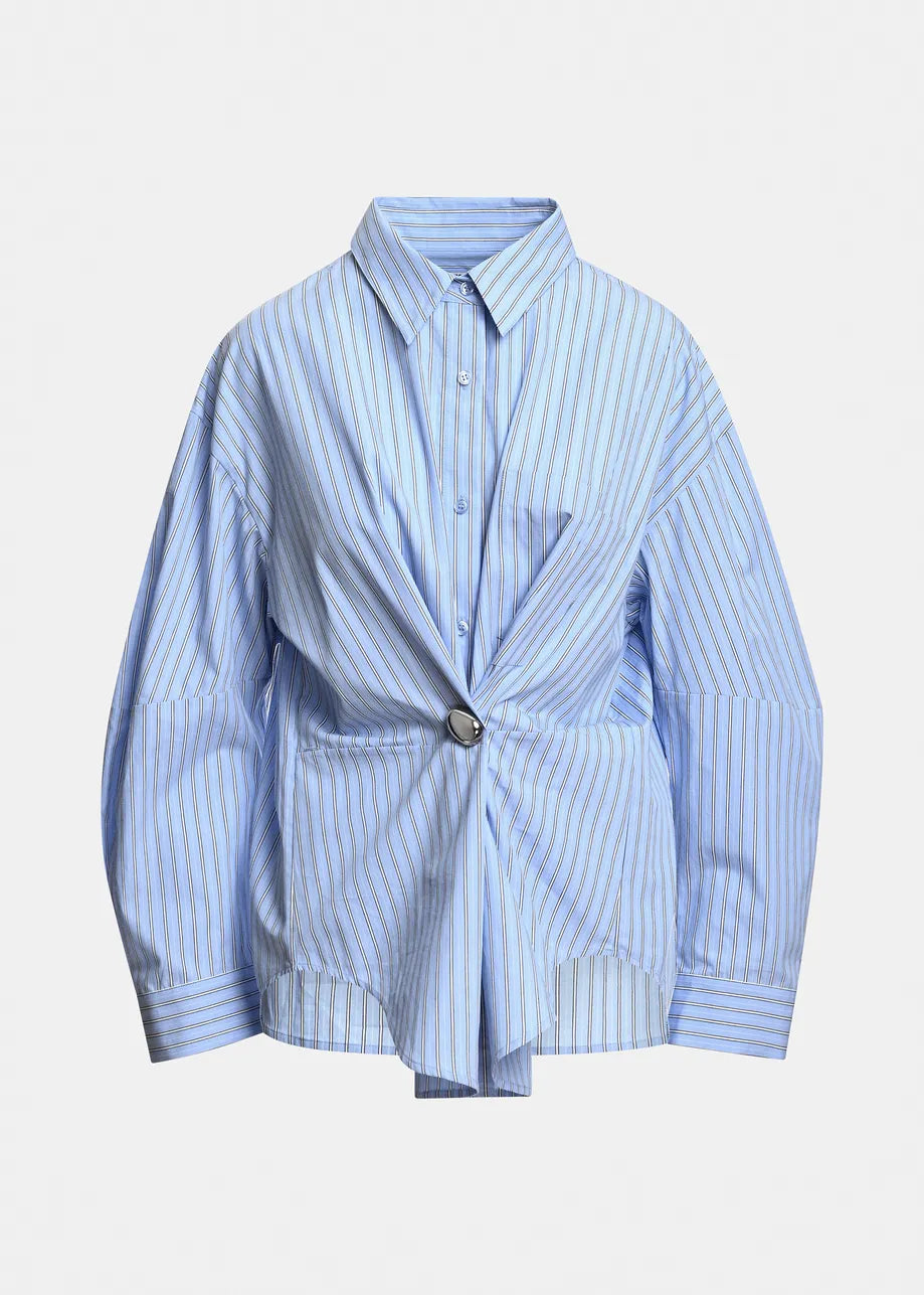 A light blue and white vertically striped button-down shirt jacket with a unique wrap-style front and a single silver-tone button closure, displayed on a clean white background.