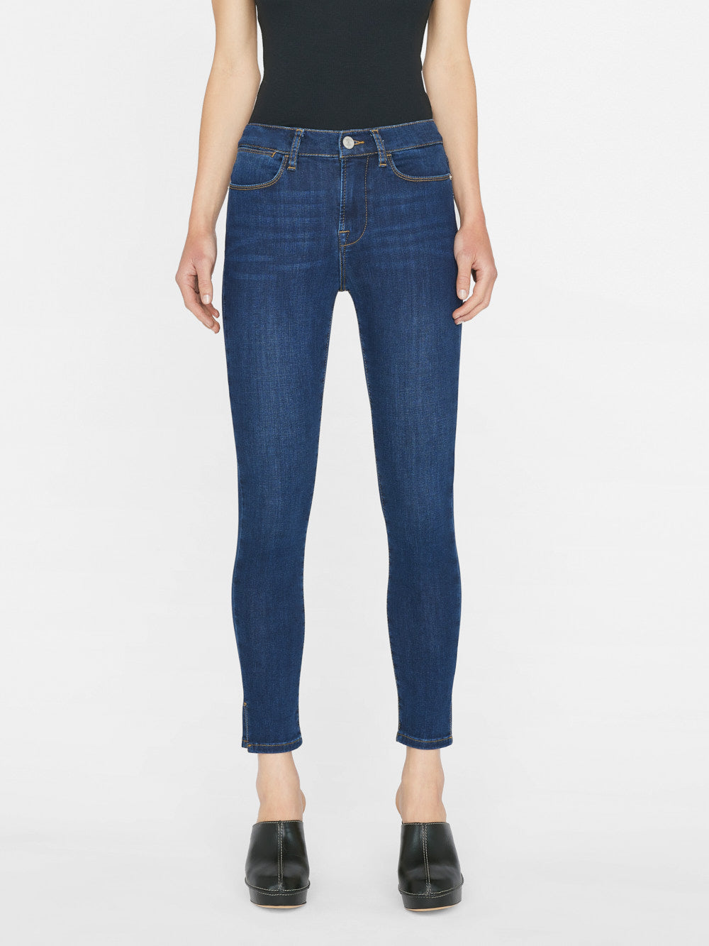 The woman showcases her Frame Le High Skinny Outseam Slit - Majesty jean, a form-fitting silhouette crafted from a sustainable stretch cotton blend.
