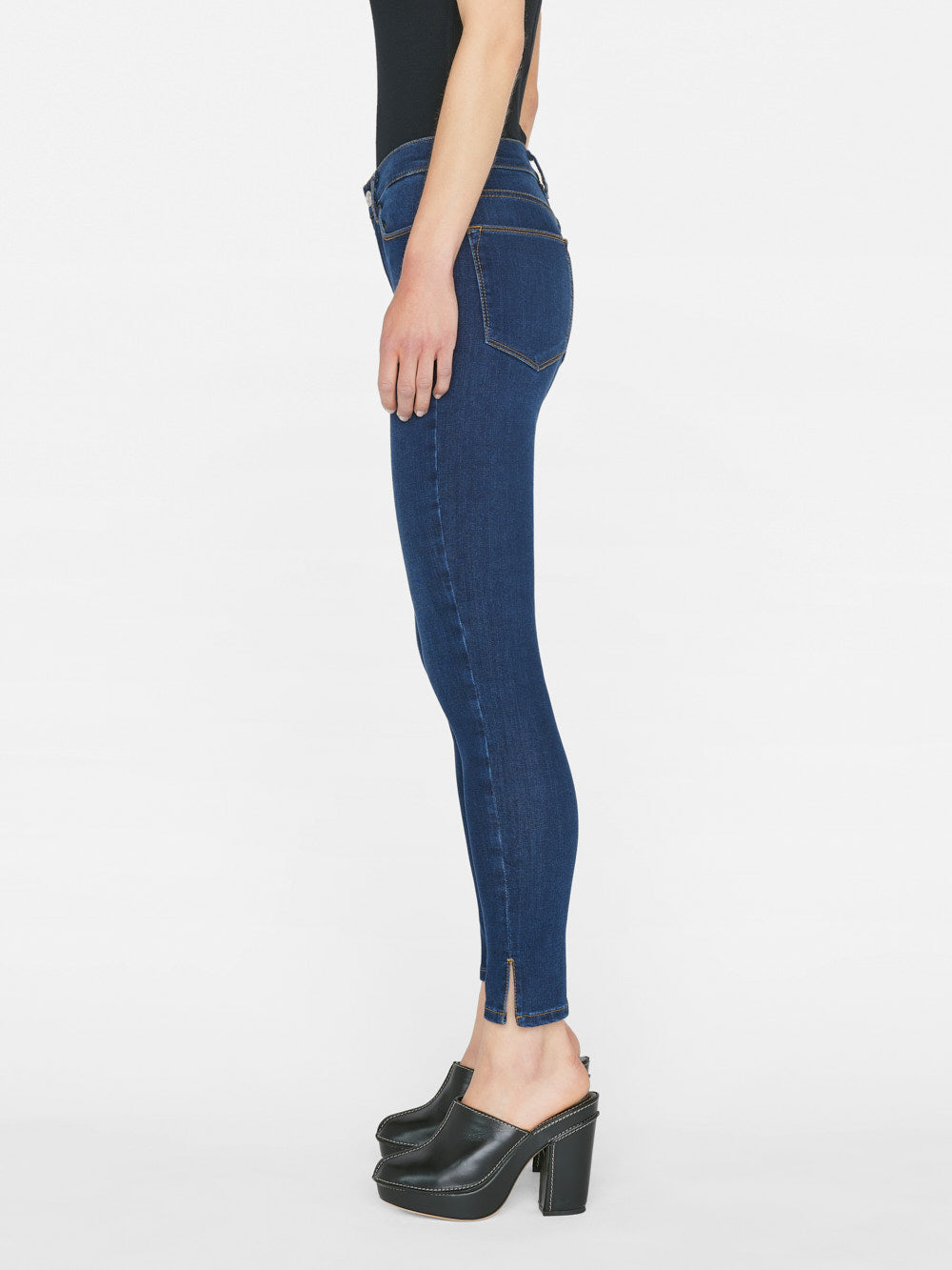 The back view of a woman wearing a pair of Frame Le High Skinny Outseam Slit - Majesty jeans, showcasing the form-fitting silhouette and sustainable stretch cotton blend.