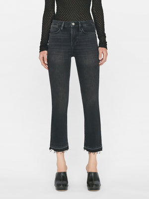 woman wears black top and blazer with a high rise washed black denim jean with a straight leg and raw hem at the ankle.