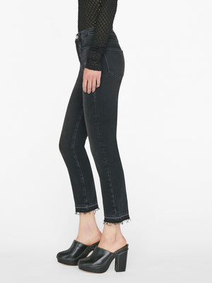 woman wears black top and blazer with a high rise washed black denim jean with a straight leg and raw hem at the ankle, showing side view