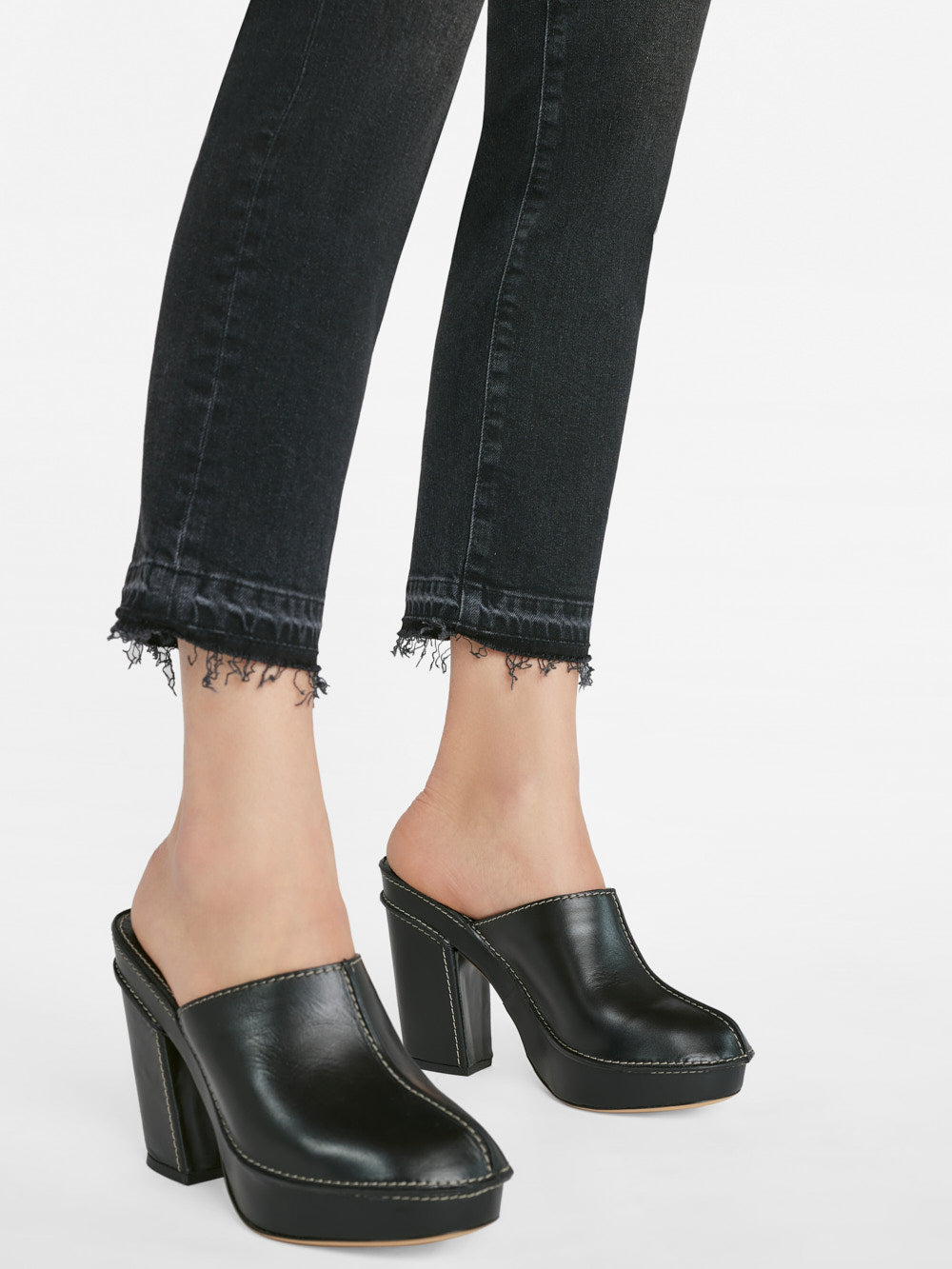A woman wearing Frame's Le High Straight Released Hem - Hutchison jeans and black mule shoes.