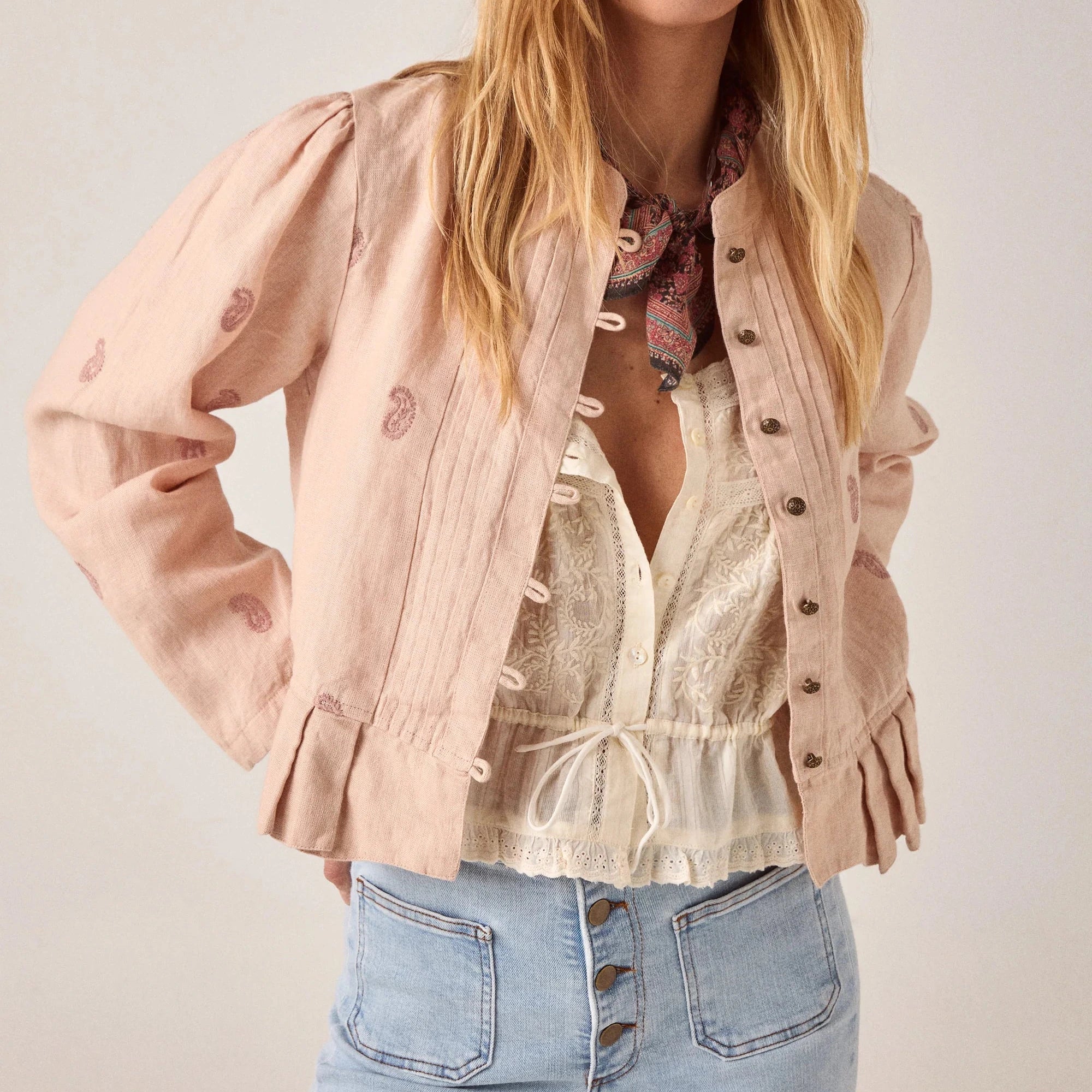 woman wears maison hotel edgar jacket in blush rose pink with light coloured jeans on a white background