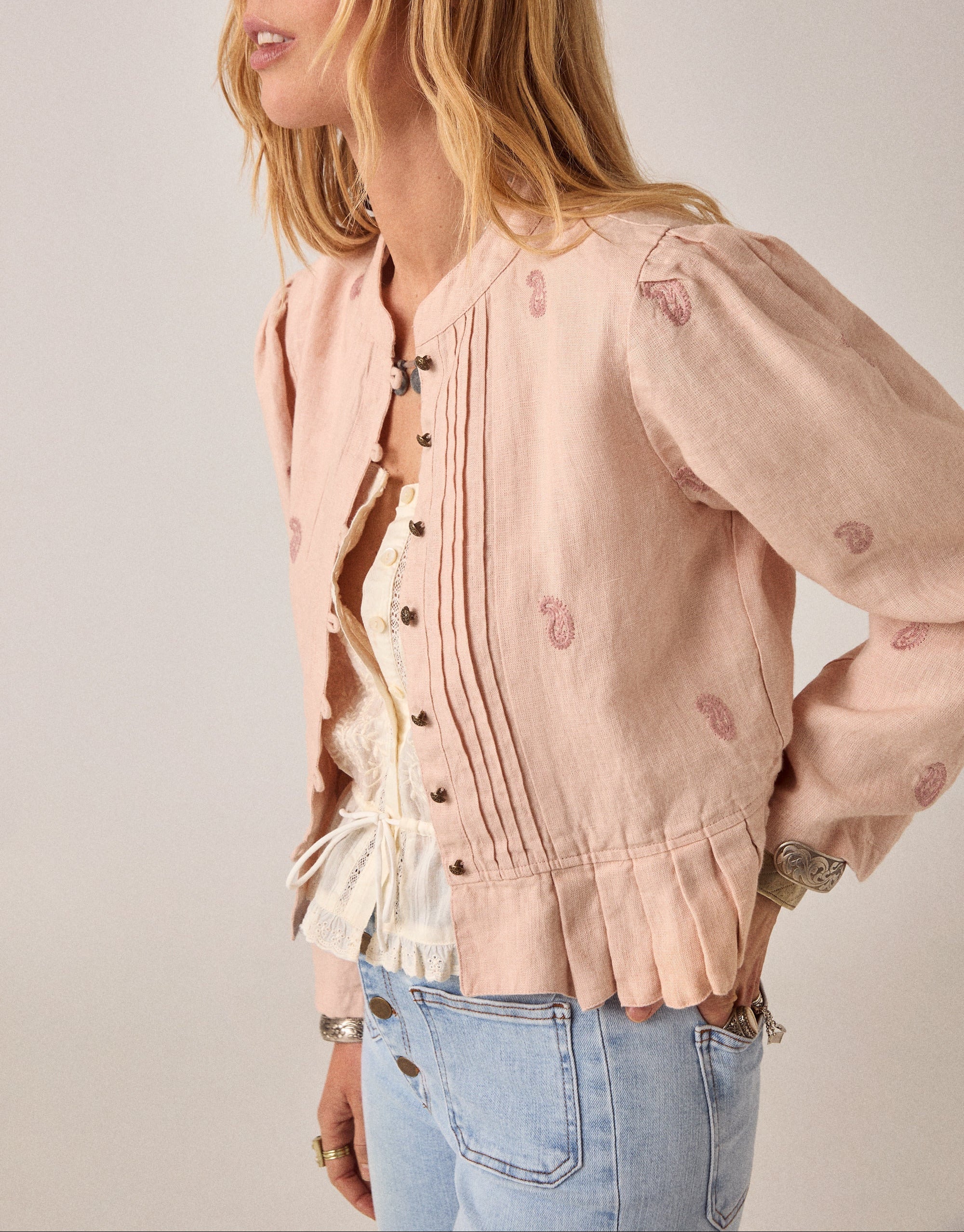 woman wears maison hotel edgar jacket in blush rose pink with light coloured jeans on a white background