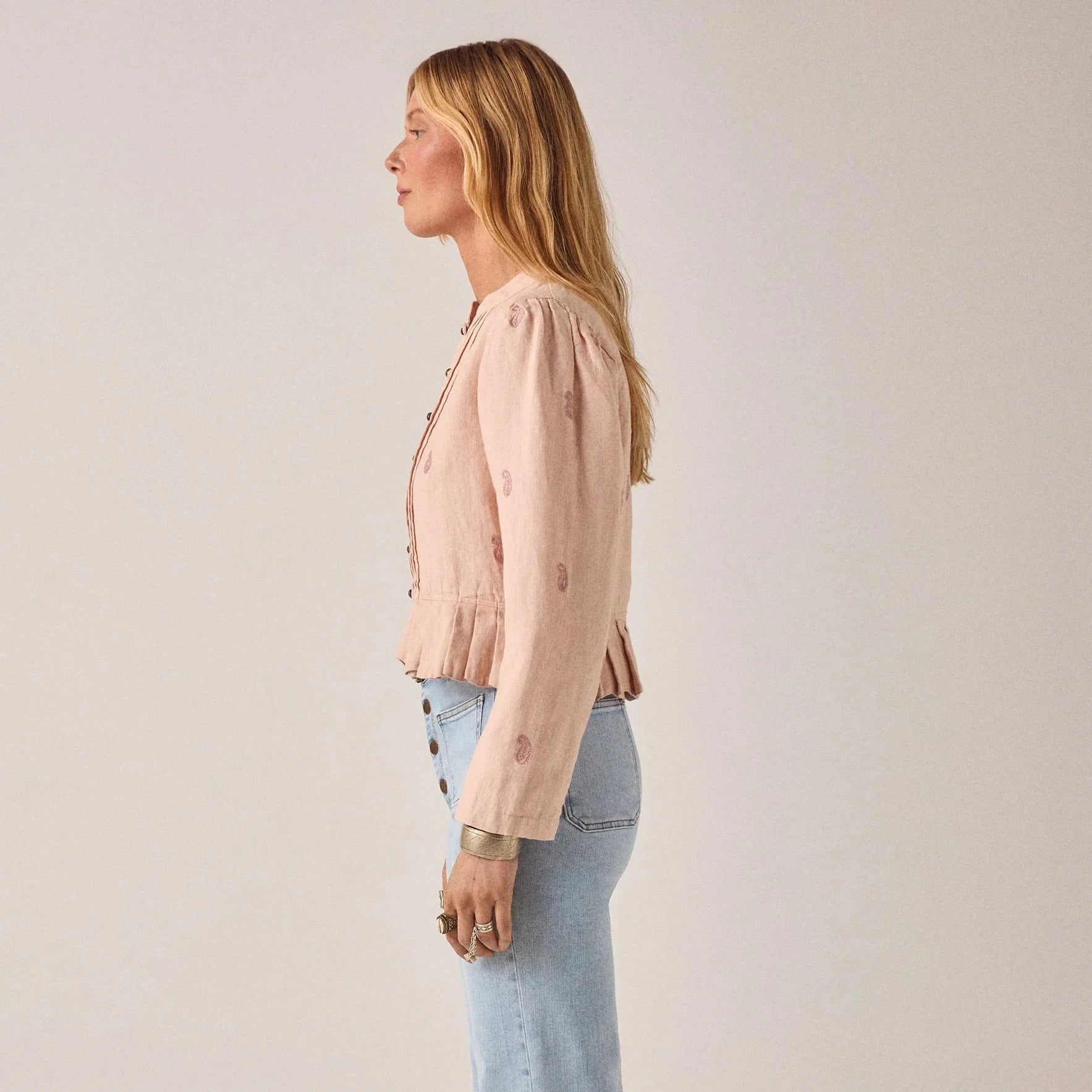 woman wears maison hotel edgar jacket in blush rose pink with light coloured jeans on a white background