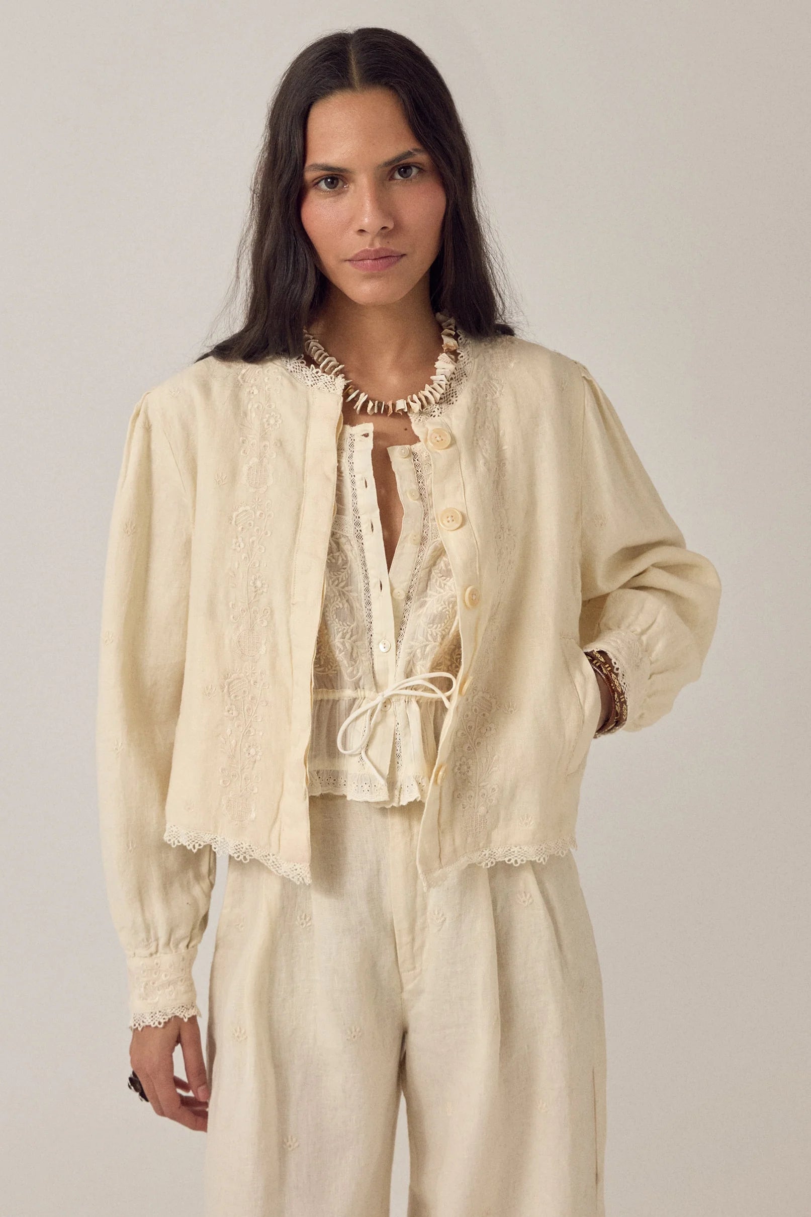woman wears maison hotel otelo cotton and linen summer jacket in cream with linen trousers on na white background