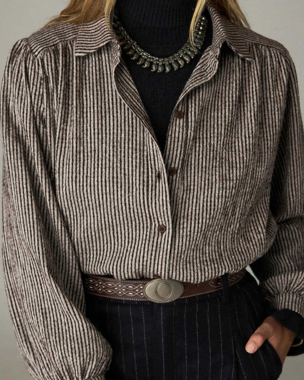 Maison Hotel Claude Blouse - Coffee Stripes with a gathered yoke, worn over a black turtleneck with a decorative silver necklace and a brown leather belt.