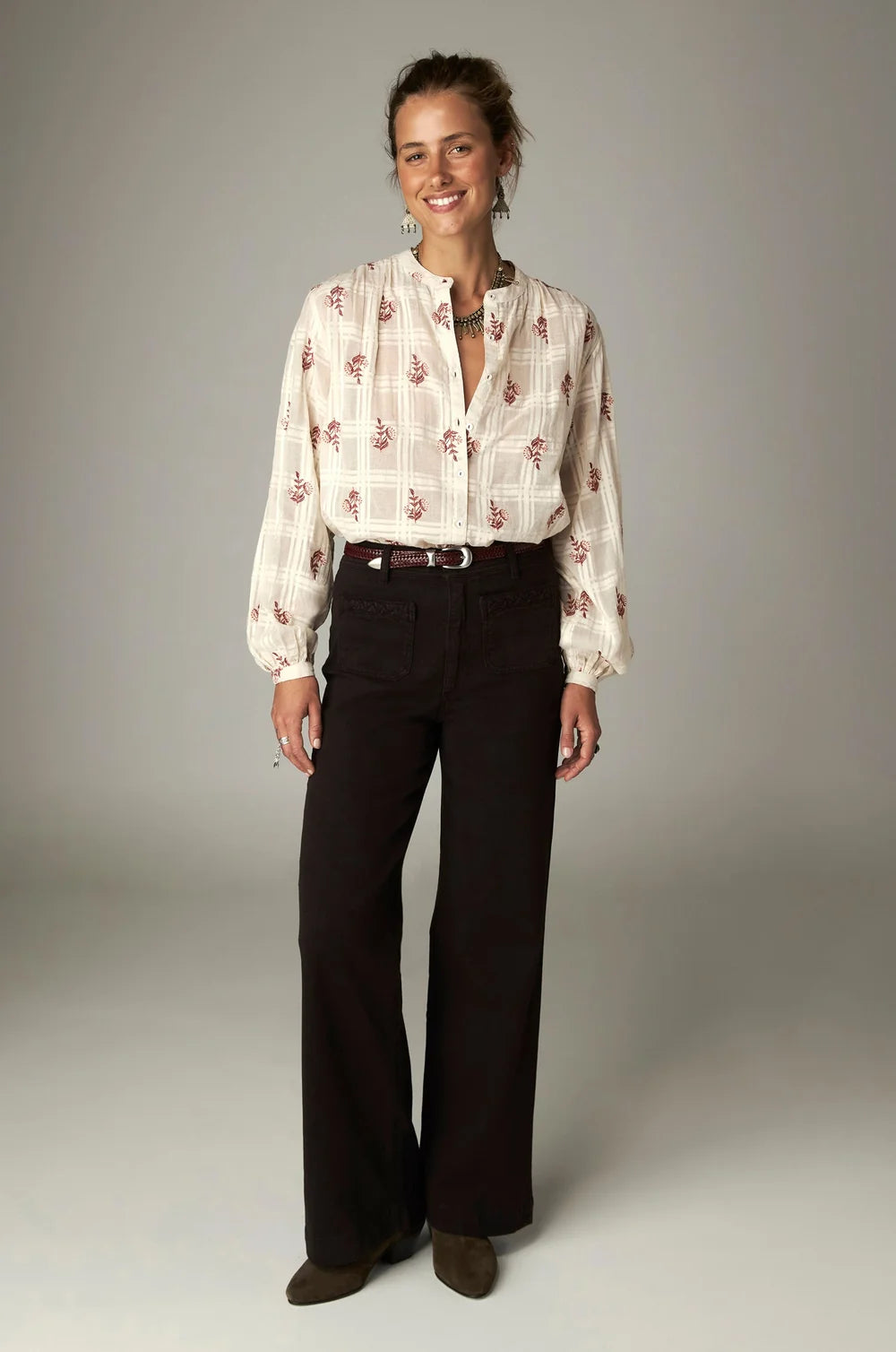 A woman wears a cream-colored, long-sleeved blouse with a red leaf pattern and coffee-hued, high-rise wide-leg Giulietta Pant - Coffee.