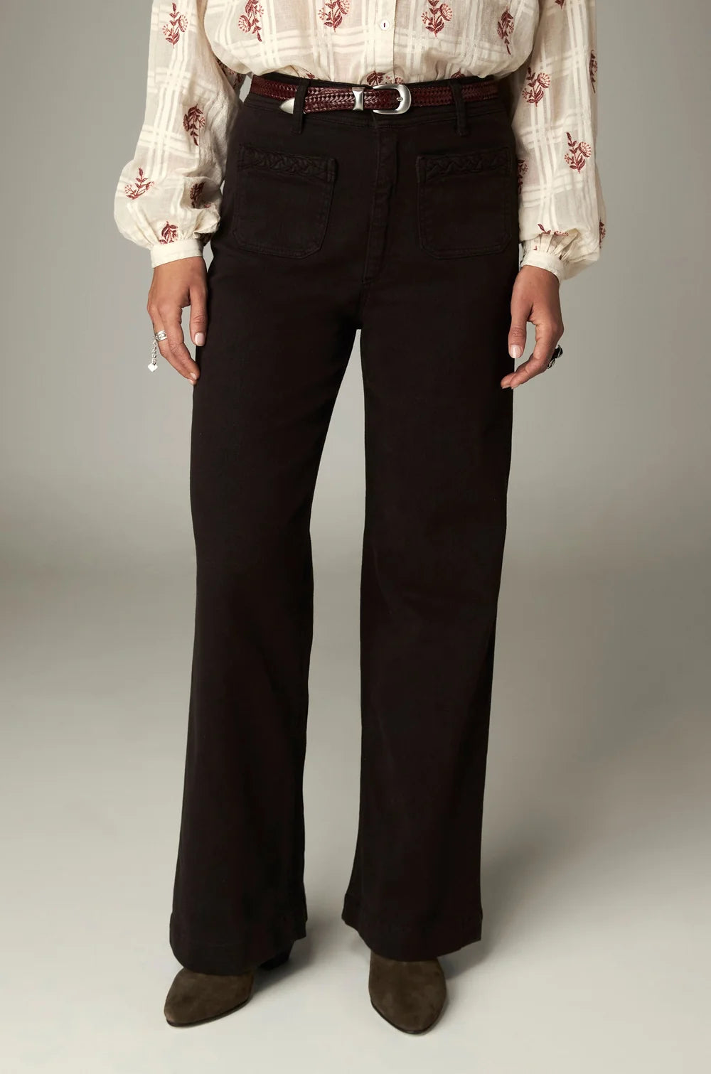 A person wearing coffee-hued Giulietta Pant high-rise wide-leg trousers with front patch pockets and a thin braided belt.