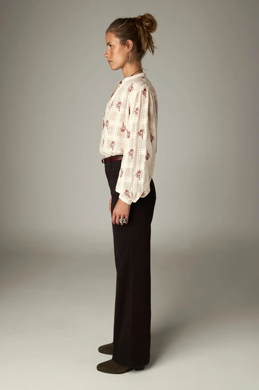 A side view of a person wearing a cream-colored floral blouse and high-rise, wide-leg Giulietta Pant - Coffee.