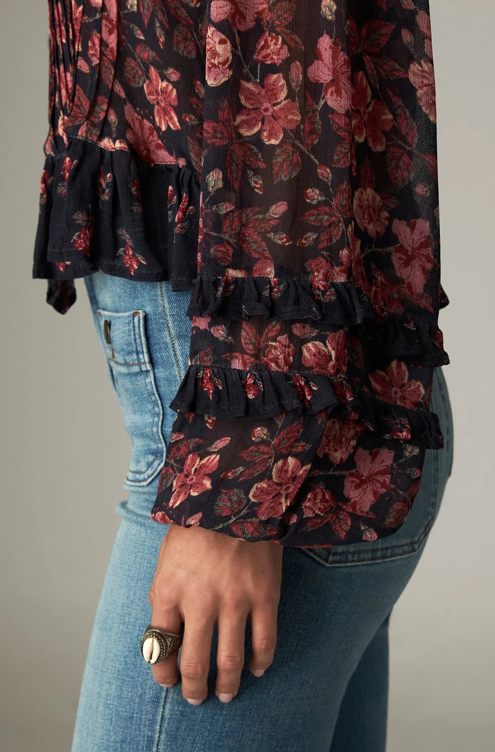 Lerele Blouse - Punk Pink featuring a relaxed-silhouette, dark floral print, and ruffle details on the cuffs and bodice, worn with light blue jeans.