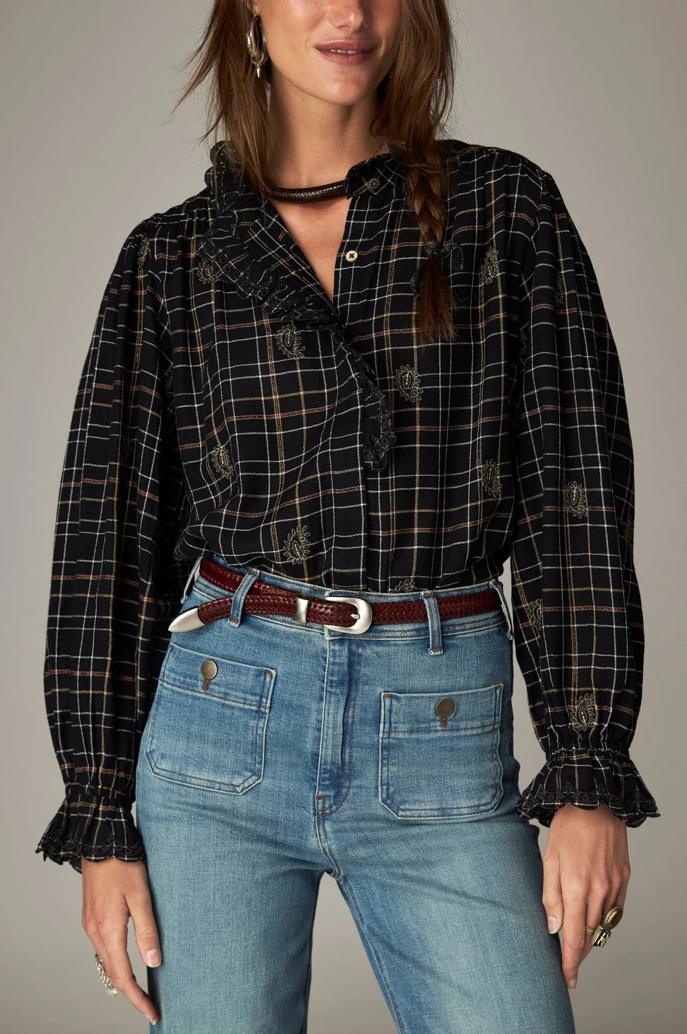 Maison Hotel Coco Blouse - Noir Plaid with a ruffled collar and cuffs, worn with blue jeans and a thin braided belt.