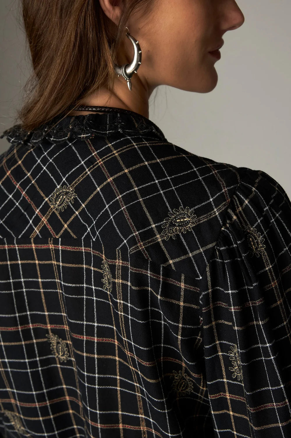 Close-up back view of a Maison Hotel Coco Blouse - Noir Plaid with metallic thread embroidery and a lace collar.