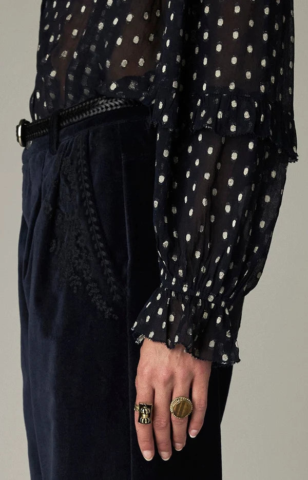 Simona Blouse - Sienna navy in metallic jacquard with ruffle detailing, worn with dark trousers and two rings.