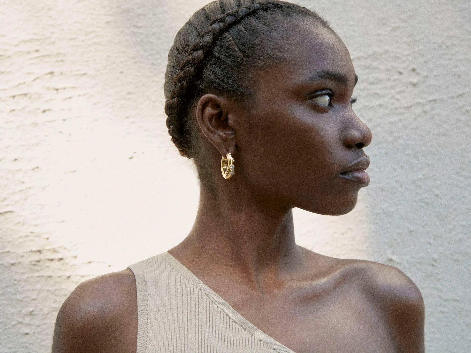 A black woman wearing a tan dress and medium-sized SHYLA - Oren Hoops - Gold earrings by Shyla.