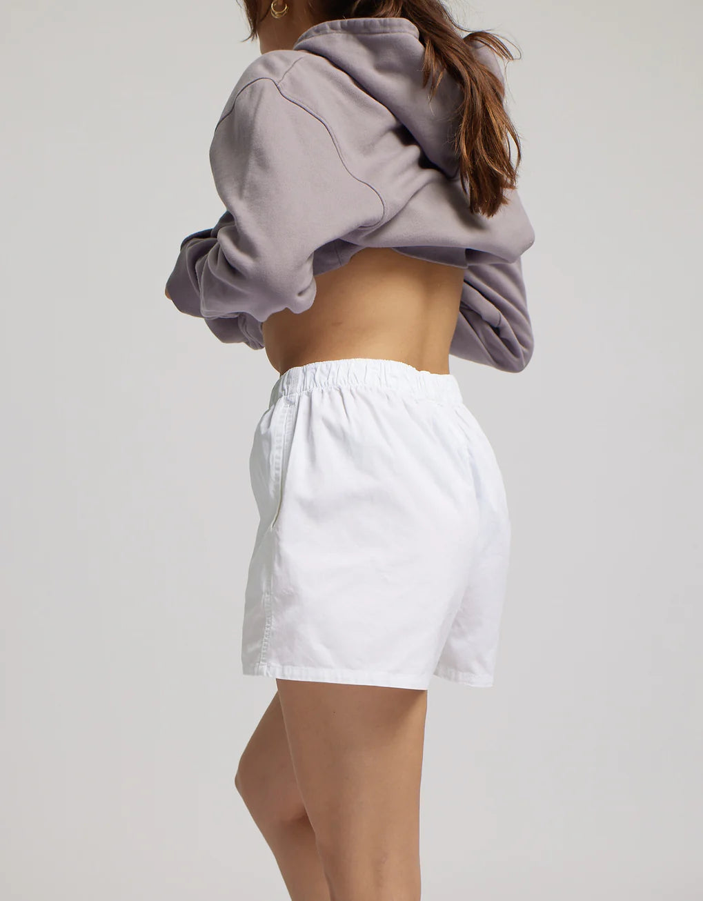 A woman from behind wearing a cropped hoodie and Colorful Standard's durable, organic twill shorts.