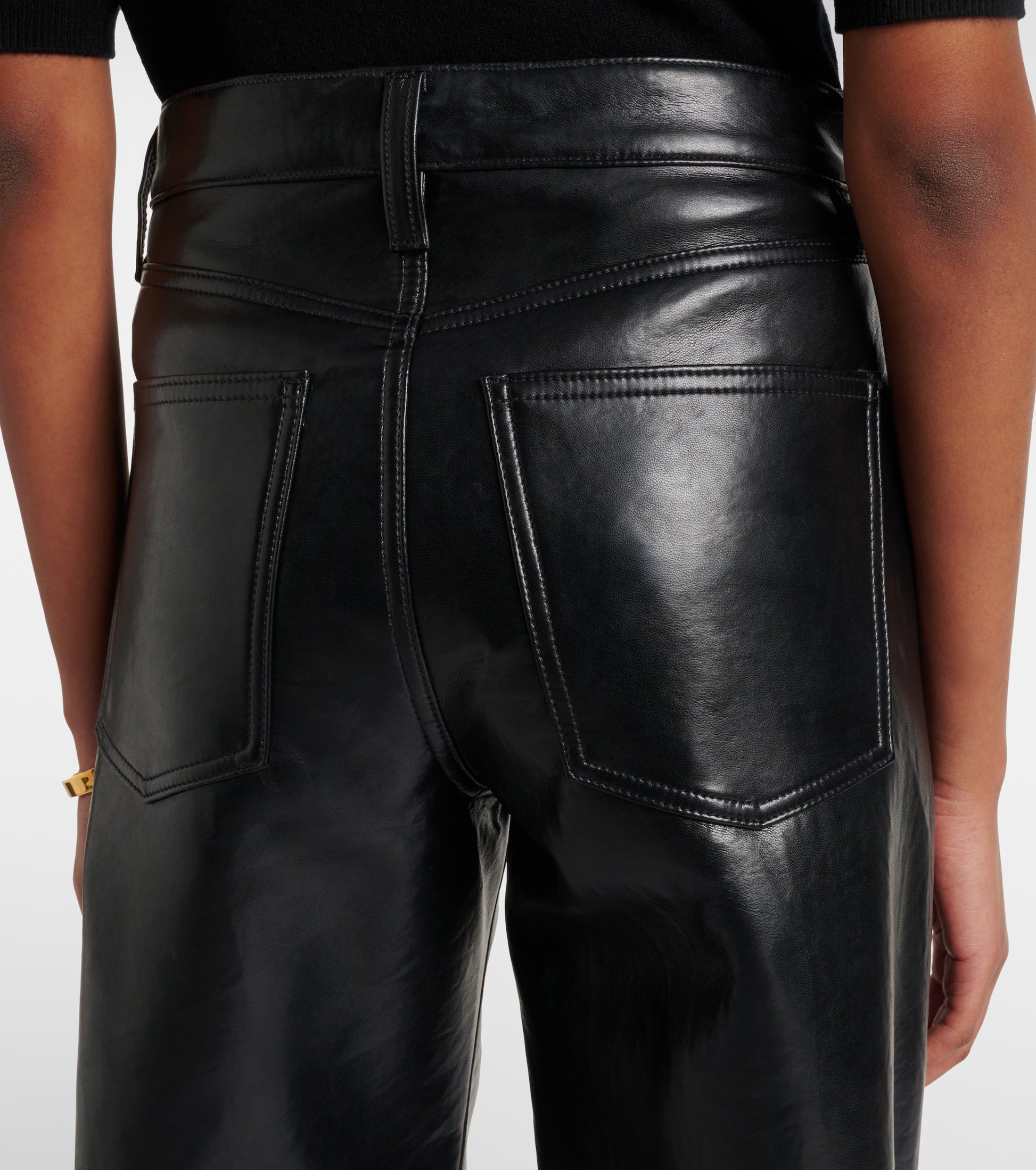 A person wearing AGOLDE Arc Jean 32 Wide Leg Trousers - Detox, high-waisted black leather pants crafted from recycled leather, shown from the back with visible stitching and large back pockets.