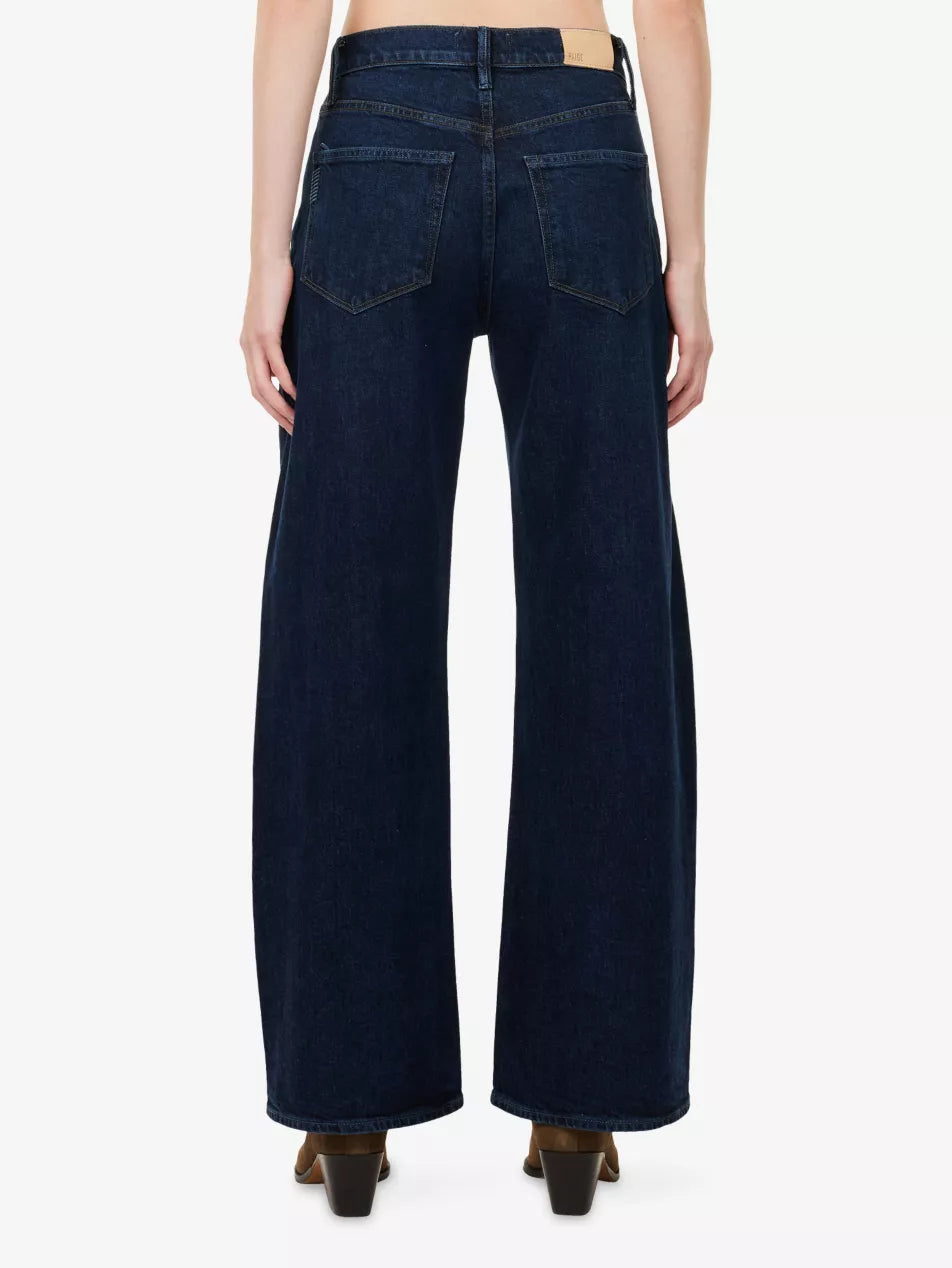 Person wearing Paige Arellia Skimmer Barrel Leg - Visage denim high-rise jeans in a dark vintage wash and brown heeled shoes, shown from the back against a plain white background.