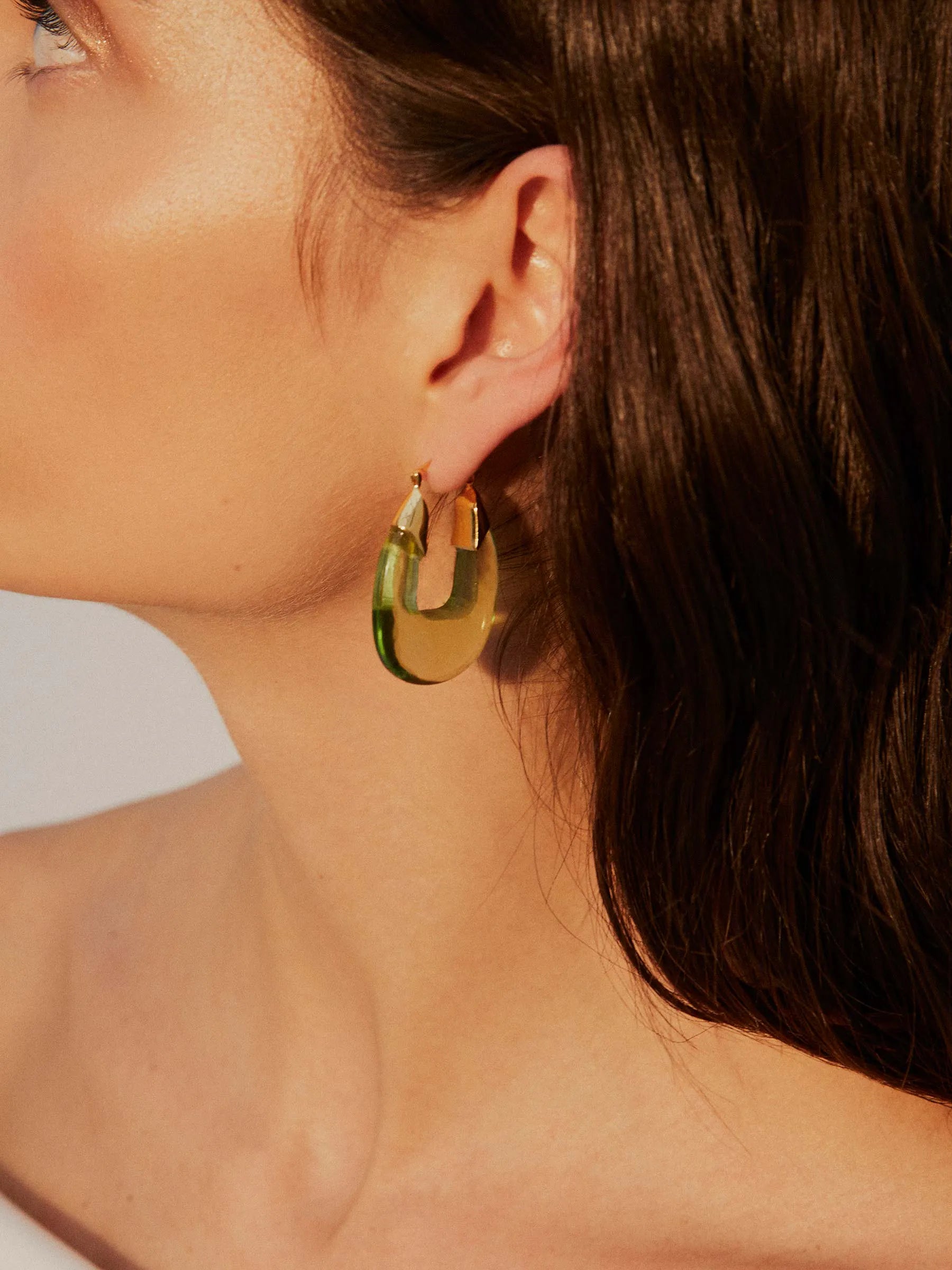 The model is wearing a pair of SHYLA - Rafelli Earrings - Gold hoop earrings.