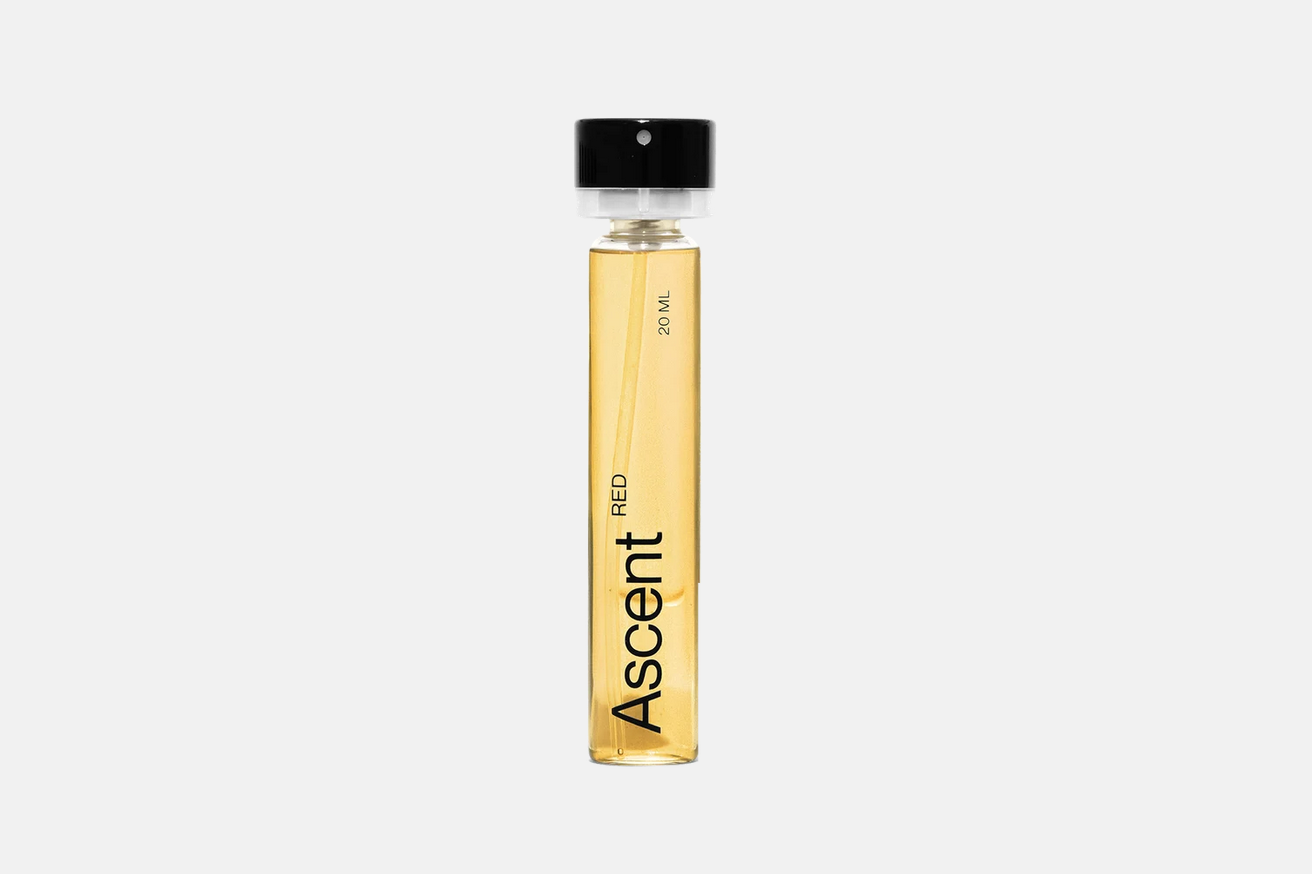 Cylindrical glass Ascent Refillable Perfume - Red vial containing golden amber-woody fragrance, with a black cap and label reading “Ascent RED 20 mL.”