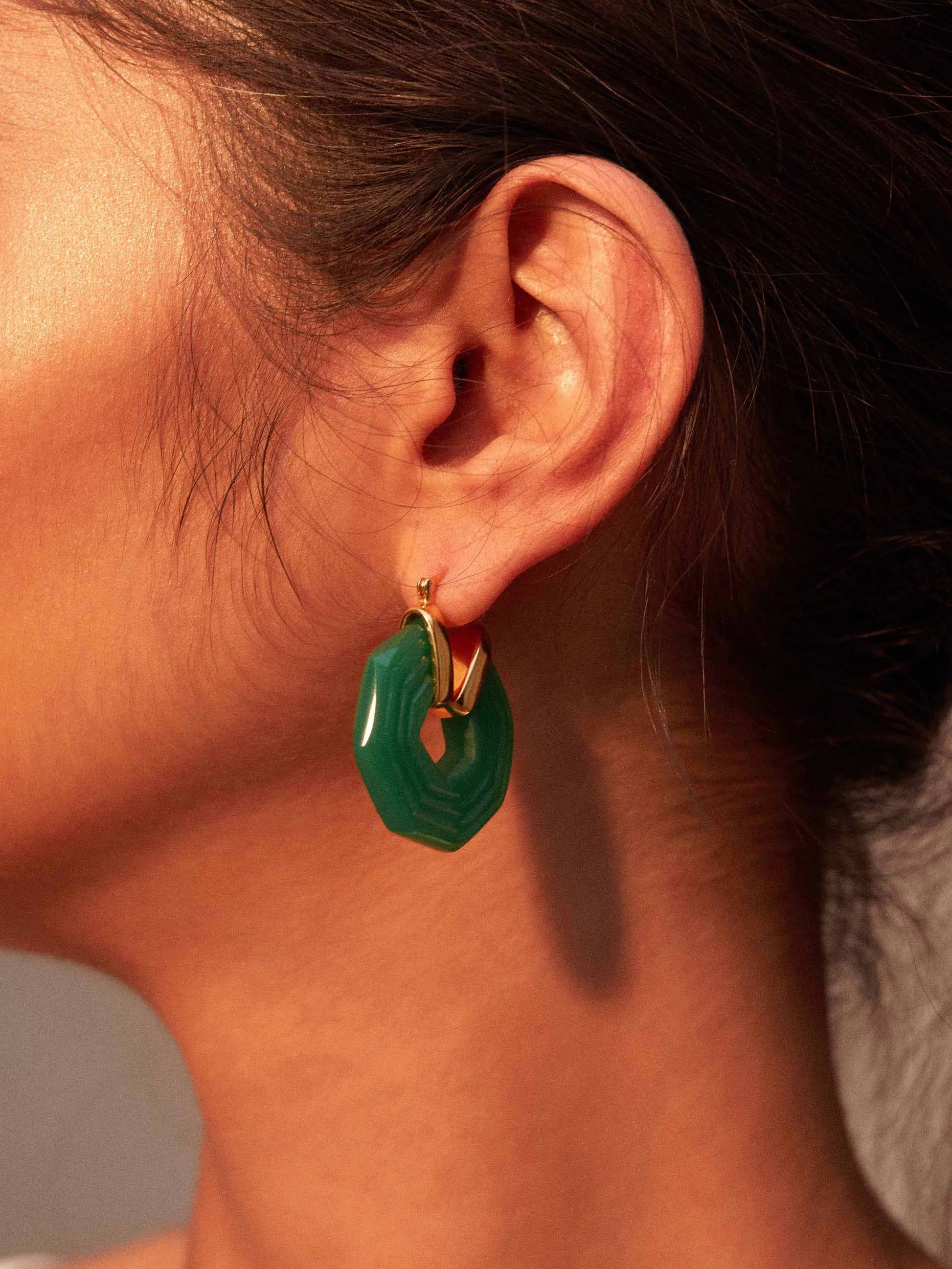 A close up of a woman's ear with a Shyla - Sphinx Earrings - Emerald.