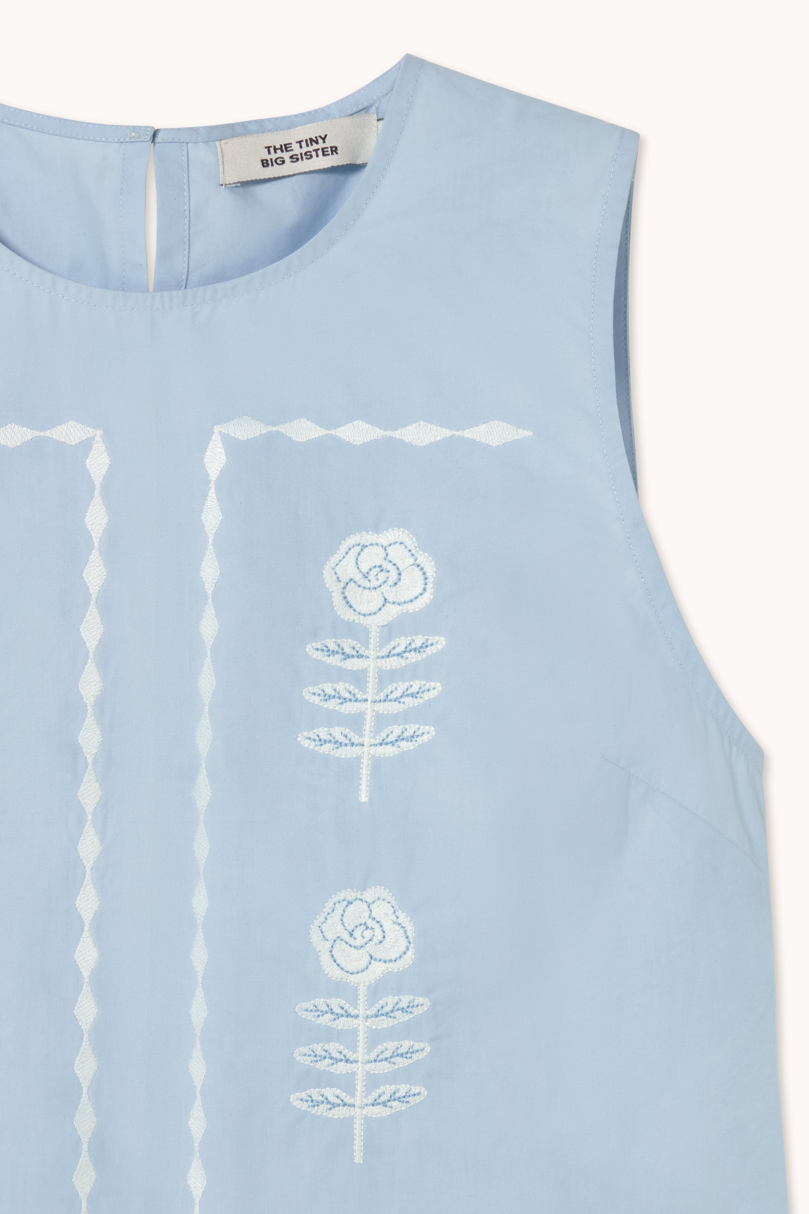 Tiny Big Sister's Embroidered Sleeveless Top in blue features delicate white floral embroidery and a keyhole button closure at the back neckline.