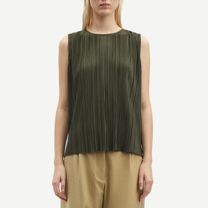 A person wearing a sleeveless, forest night Sauma O Neck Top by Samsøe Samsøe, made from recycled polyester, and tan trousers is standing against a plain white background.