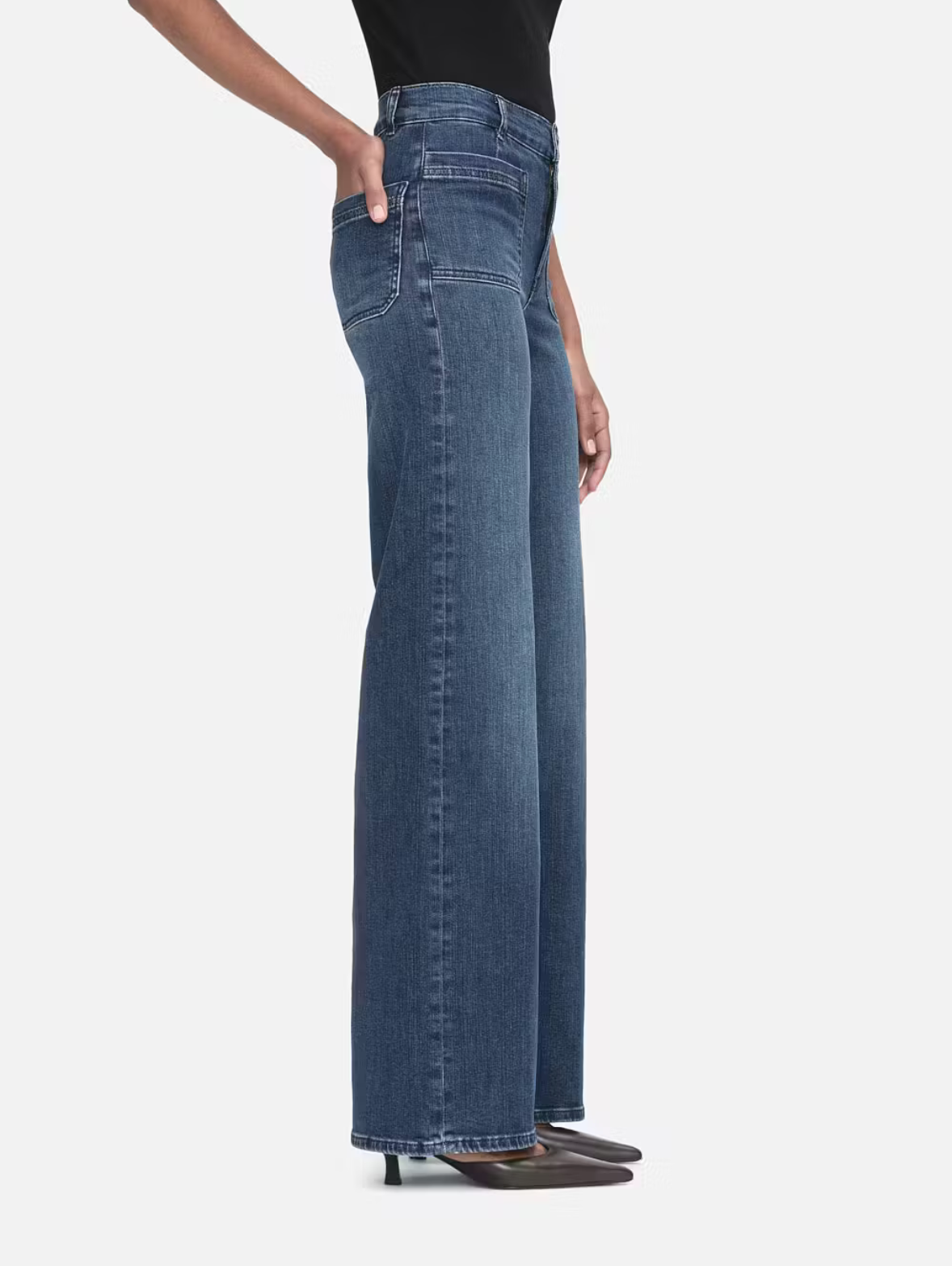 Model wears wide leg jeans in a dark wash. Features front pockets. Side view.