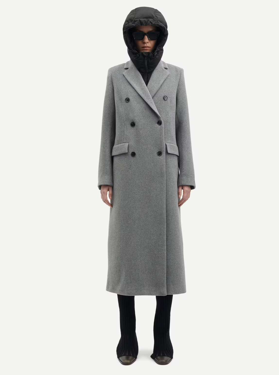 A person wearing the sophisticated Falcon Coat - Grey Melange by Samsøe Samsøe, paired with a black hood and dark sunglasses, stands against a white background.