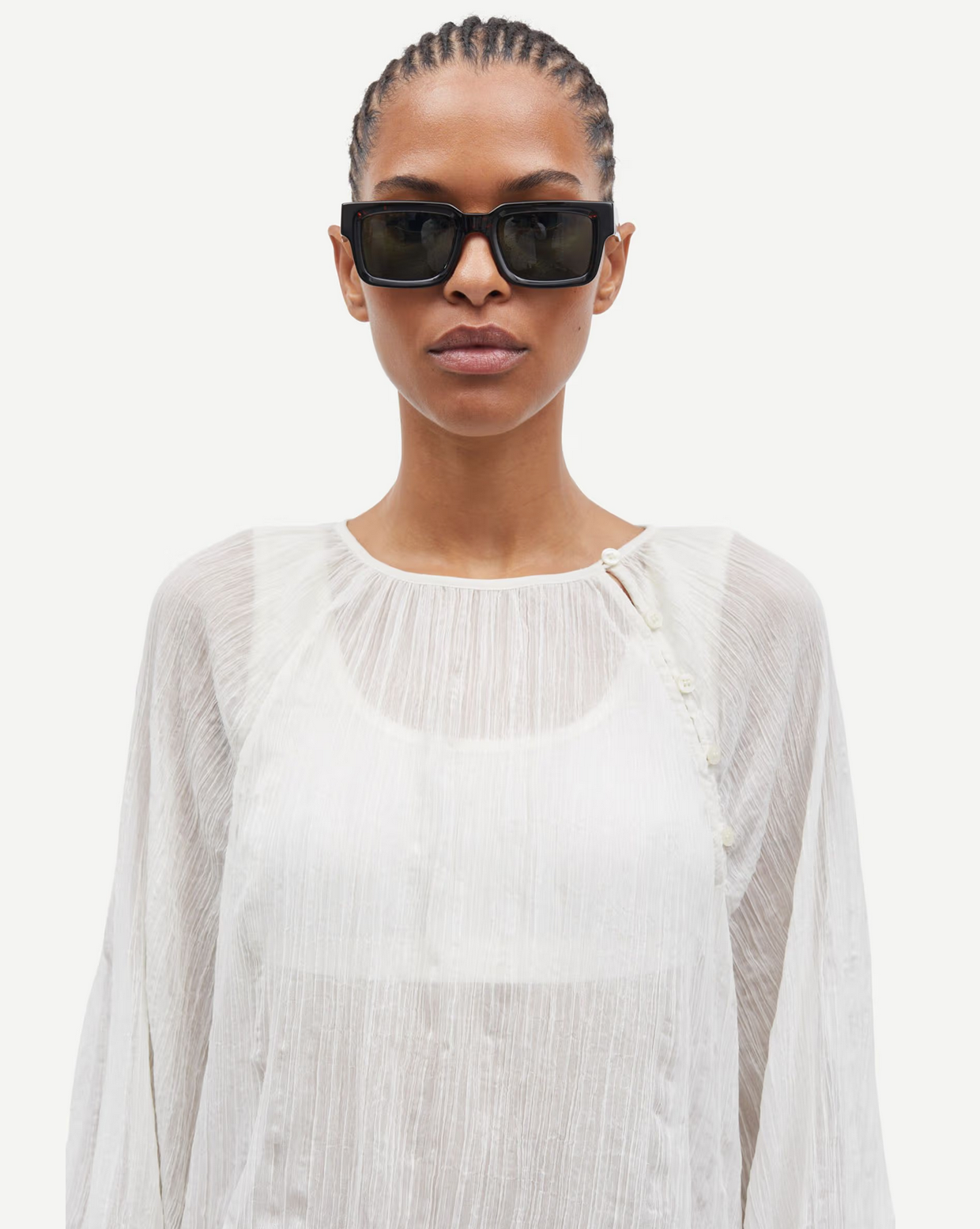 Wearing Samsøe Samsøe's Savira Blouse in Egret, a person with black sunglasses poses against a plain white background.