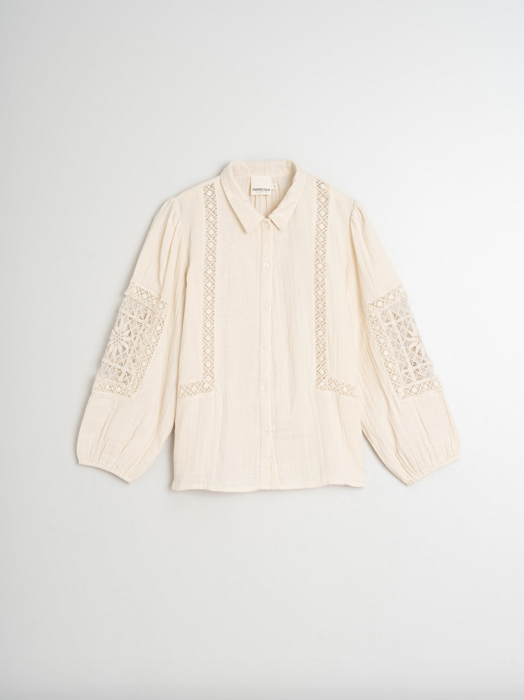 Indi & Cold's Double Gauze Shirt in ivory features a button-up design crafted from double gauze cotton with intricate lace inserts on the sleeves and front.