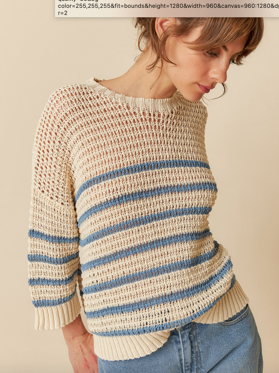 A person wearing the Indi & Cold Dual Stripe Sweater - Indigo, featuring blue and beige tones, is looking downward against a neutral background.