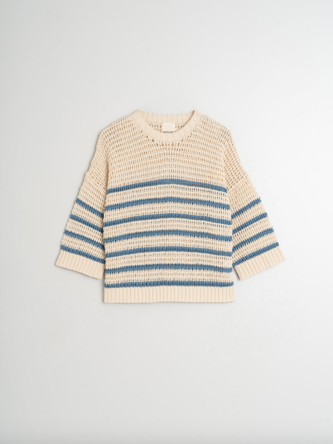 The Dual Stripe Sweater - Indigo by Indi & Cold is a versatile cream-colored knit with blue horizontal stripes and a modern cropped fit, set against a plain background.