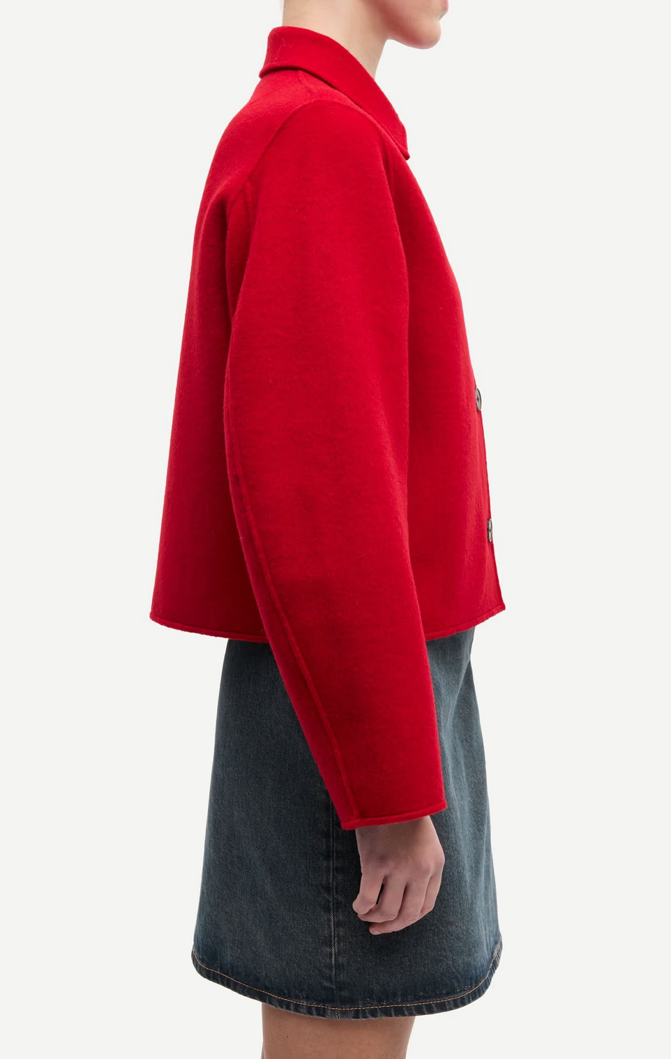 A person wearing the Samsøe Samsøe Saholly Jacket in Haute Red with long sleeves and a dark denim skirt, photographed from the side against a plain white background.