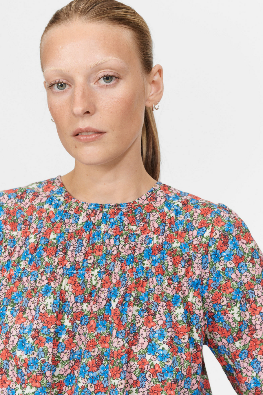 a woman wears a floral printed blouse by nue notes on a white background