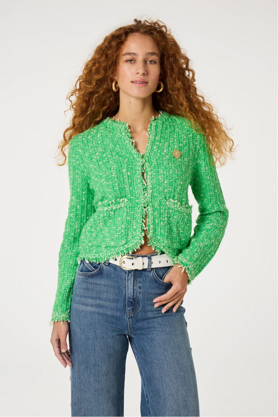 a woman stands and wears a green cardigan and jeans by fabienne chapot on a white background