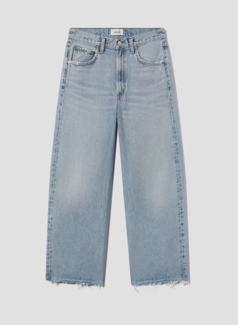 The AGOLDE Low Curve Fray - Force is a light blue, high-waisted jean in regenerative cotton with wide legs, raw frayed hems, five pockets, and a button fly, shown laid flat on a plain background.