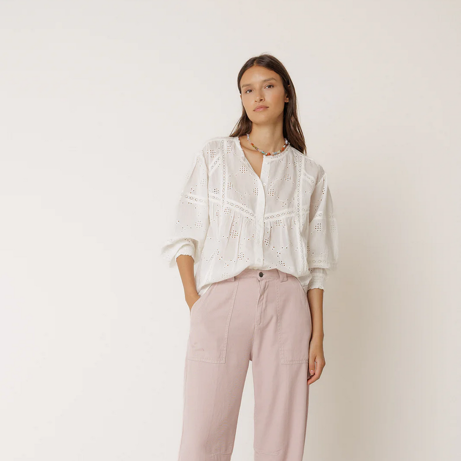 Person wearing a white shirt and pink pants on a plain background