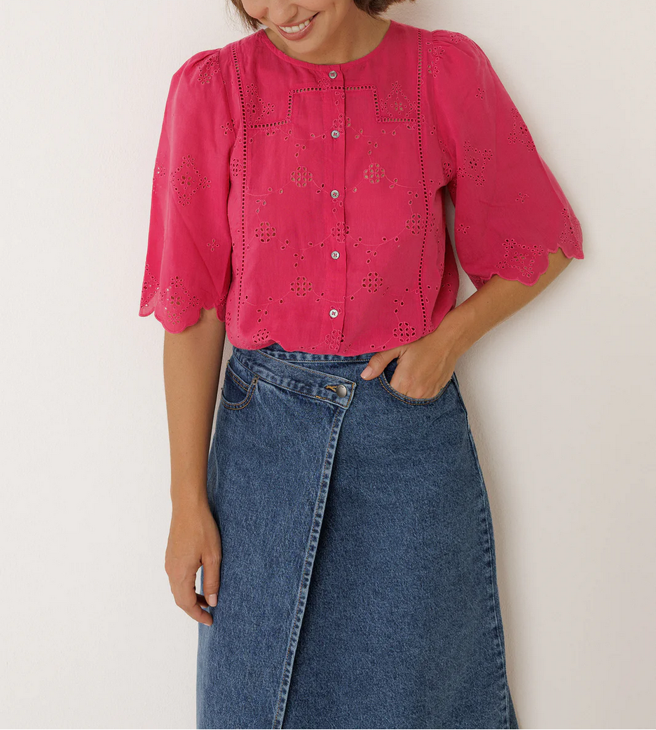 Woman wearing a pink blouse and blue jeans with 'INDI&COLD' branding.