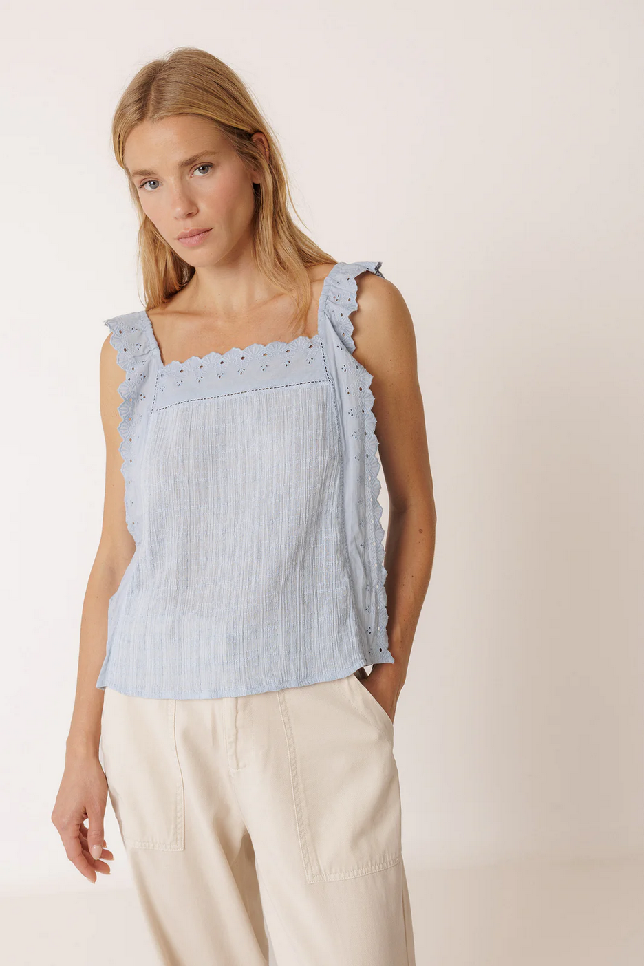 A woman wears the Indi & Cold Sleeveless Cotton Top with Lace in light blue and cream wide-leg pants, standing against a plain light background.