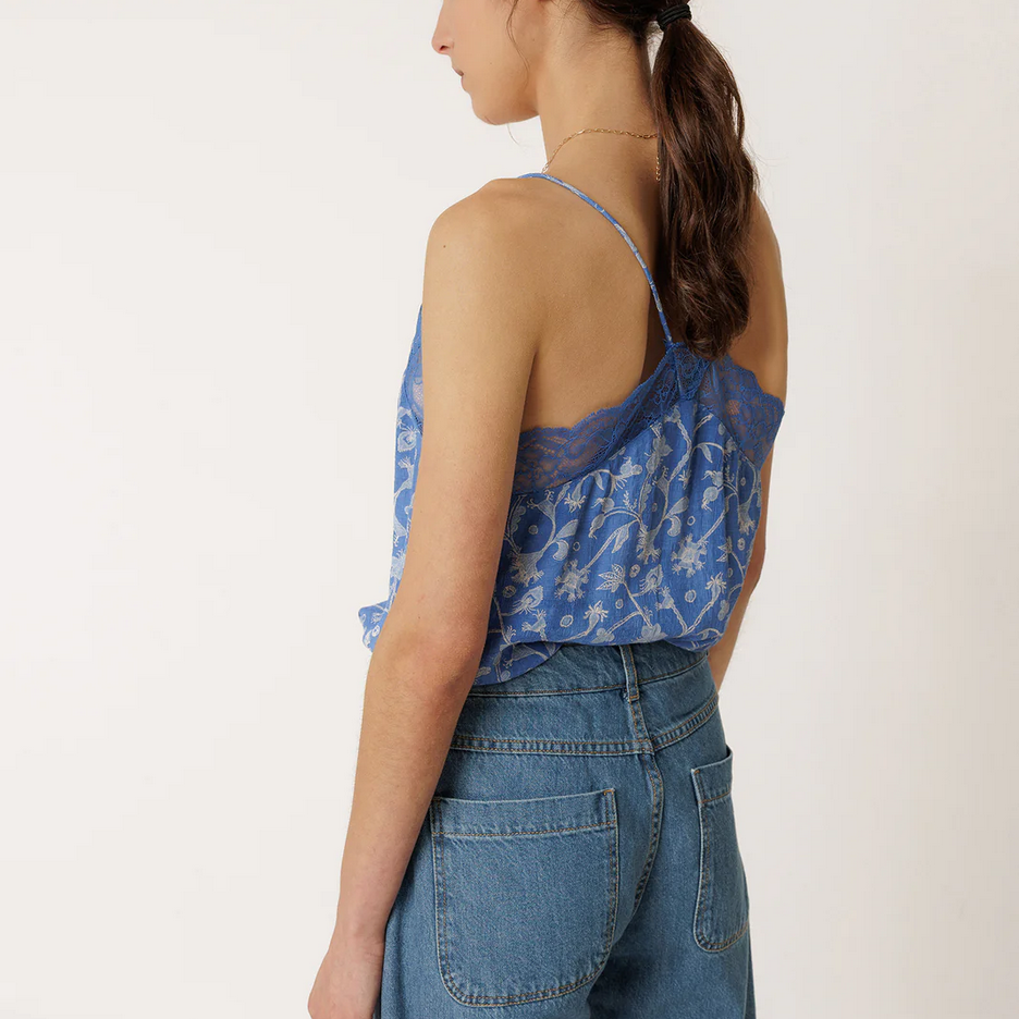 Woman wearing a blue floral top and jeans against a white background