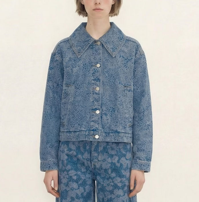 A person wears the Tiny Big Sister Laser Lace Denim Jacket in light blue, paired with matching floral jeans, standing against a plain light background.