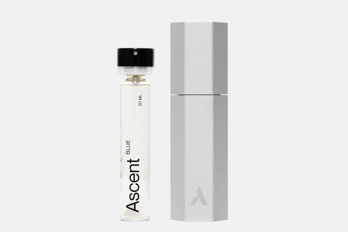 An Ascent Starter Pack - Blue 20 ML glass perfume extract vial next to a hexagonal metallic storage case.